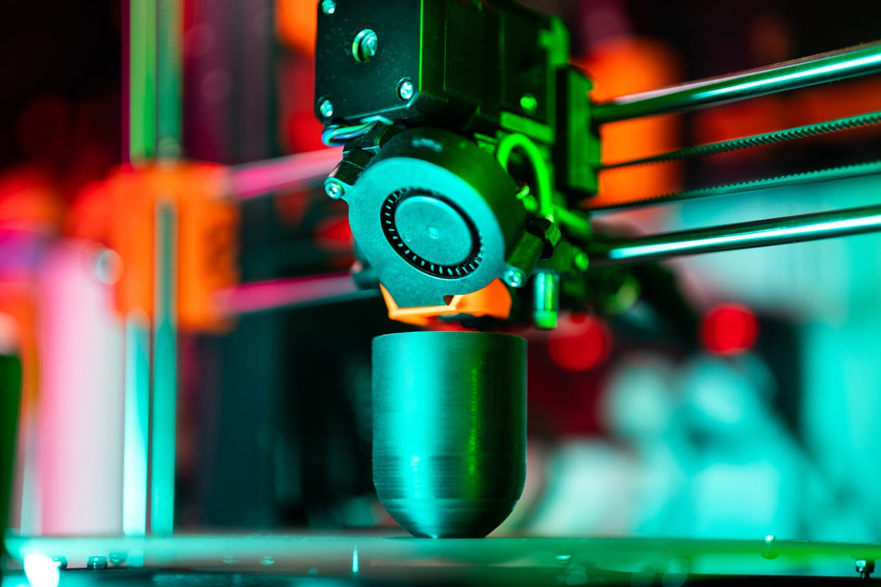 about-us Close-up of a 3D printer creating a product in neon lighting.