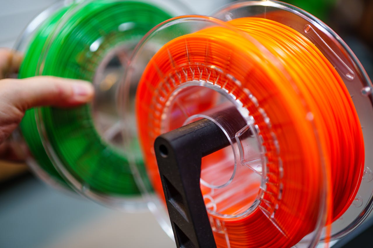 services-05 Vibrant orange and green 3D printer filament spools for innovative manufacturing uses.